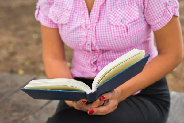 Mulher lendo um livro aberto na grama — Fotografia de Stock