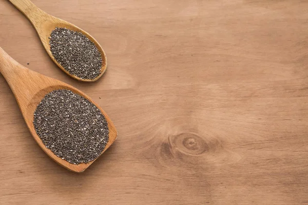 Tahta kaşıkla chia tohum ahşap arka plan üzerinde.