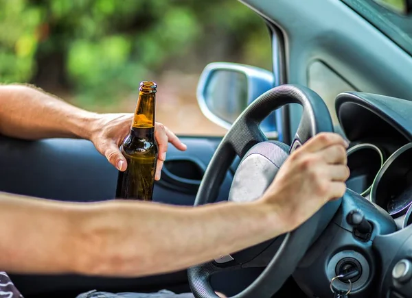 Человек пьет алкоголь за рулём автомобиля — стоковое фото