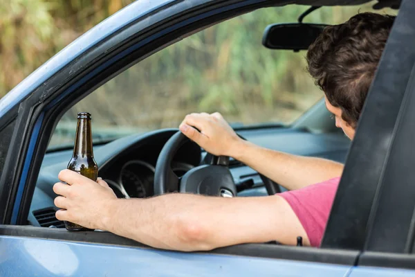 Человек пьет алкоголь за рулём автомобиля — стоковое фото