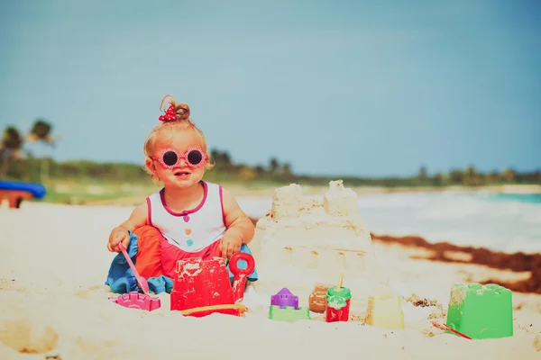Schattig klein meisje gebouw sandcastle op strand — Stockfoto