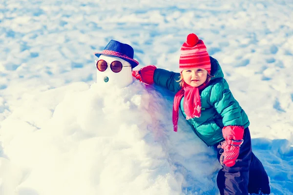 Little girl building snowman in nature — Stock Photo, Image