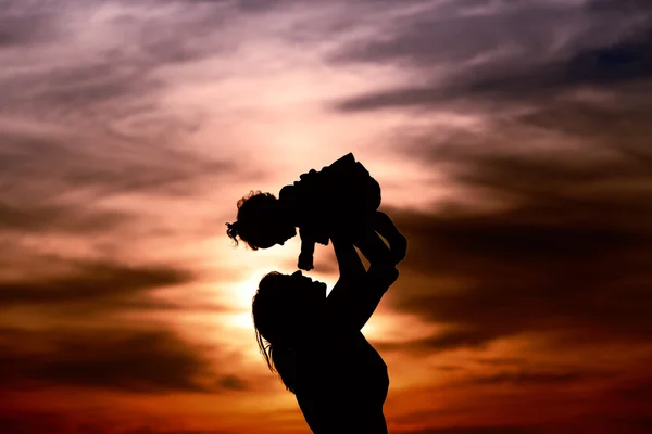 Happy mother and little daughter play at sunset — Stock Photo, Image