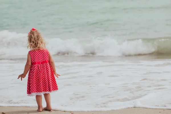 Klein meisje probeert water op strand — Stockfoto