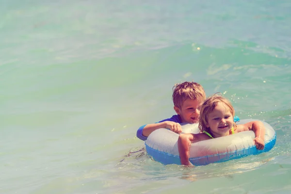 Gelukkig weinig jongen en meisje zwemmen op zee — Stockfoto