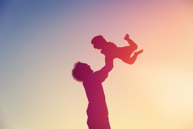 Baba ve küçük kızı gün batımında oynuyorlar.