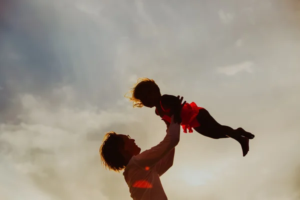 Padre e piccola figlia silhouette giocano al tramonto — Foto Stock