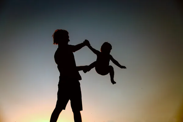 Vader en dochter silhouetten spelen bij zonsondergang — Stockfoto