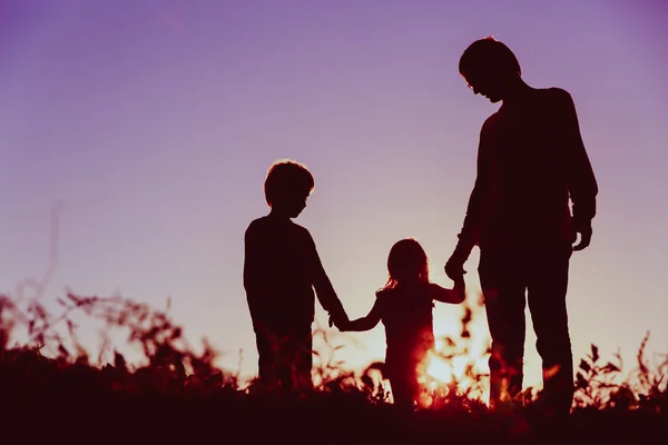 Padre con hijo e hija caminan al atardecer — Foto de Stock