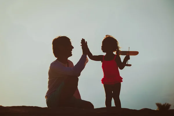 Vader en dochtertje met speelgoed vliegtuig bij zonsondergang — Stockfoto