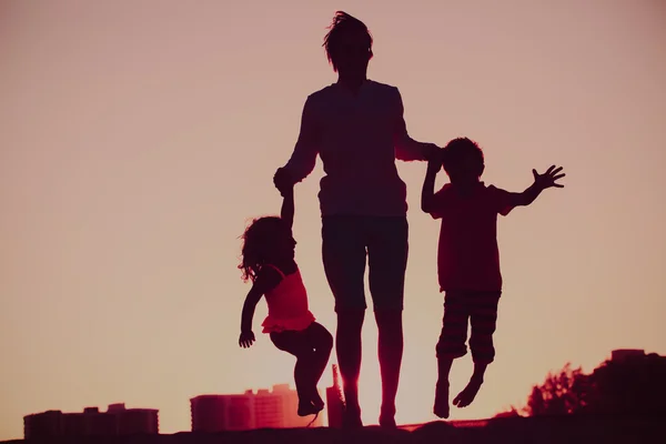 Happy family - father with kids jumping from joy at sunset — Stock fotografie