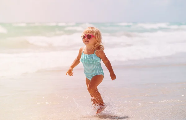 Meisje lopen spelen met golven op het strand — Stockfoto