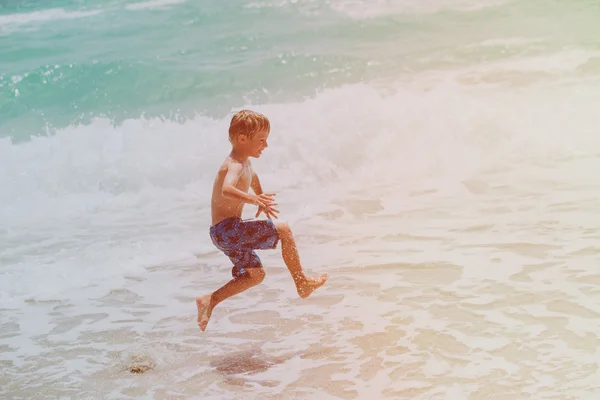 Felice bambino godere di giocare con le onde sulla spiaggia — Foto Stock