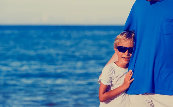 Ouderschap en strand vakantie - zoontje knuffelen vader op zee — Stockfoto