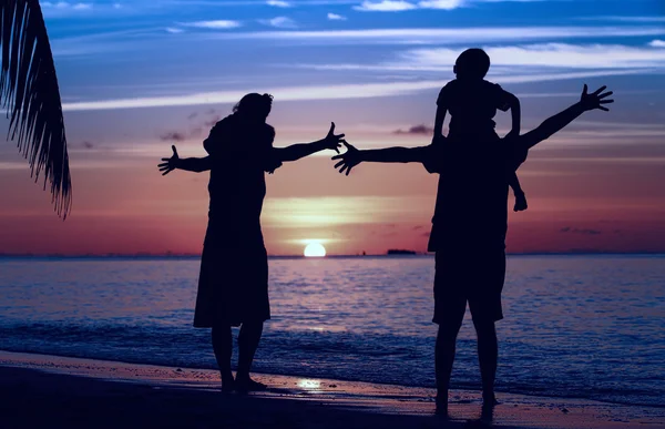 Famiglia felice con due bambini che si divertono sulla spiaggia al tramonto — Foto Stock