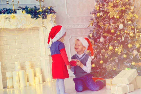 Crianças abrindo presentes de Natal na sala de estar decorada — Fotografia de Stock