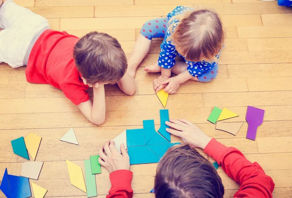 Lärare och barn som leker med geometriska former — Stockfoto