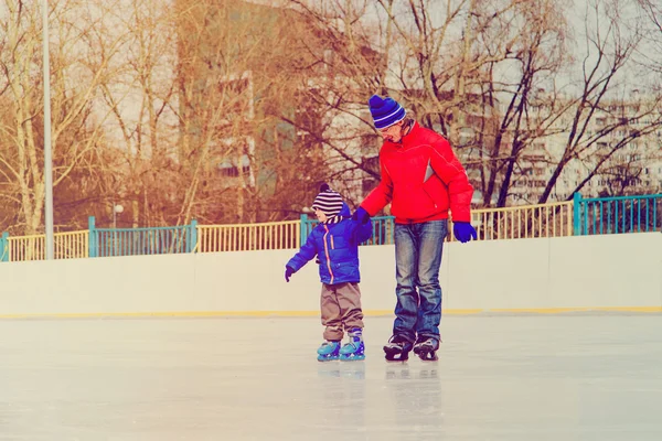 Отец и маленький сын учатся кататься на коньках — стоковое фото