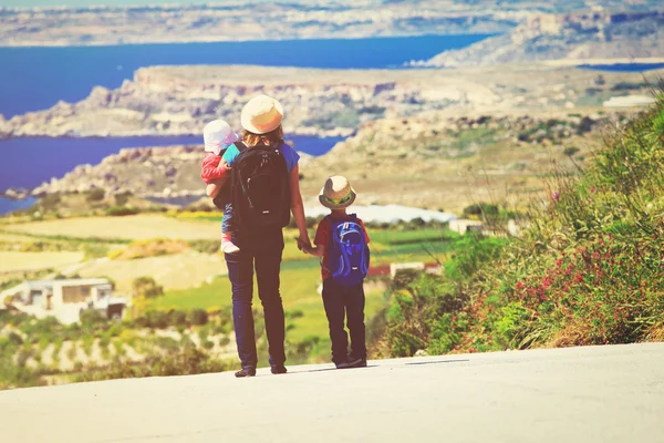 Family travel concept - mother with two kids walk on road — Stockfoto