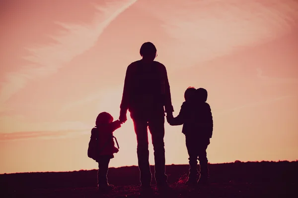 Отец с двумя детьми путешествует на закате — стоковое фото