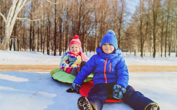 Маленький хлопчик і дівчинка ковзають в зимовий сніг — стокове фото