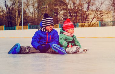küçük bir çocuk ve buz paten ile oturan kız