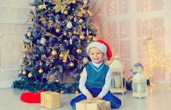 Μικρό αγόρι με τα Χριστούγεννα παρουσιάζει σε διακοσμημένο σαλόνι — Φωτογραφία Αρχείου