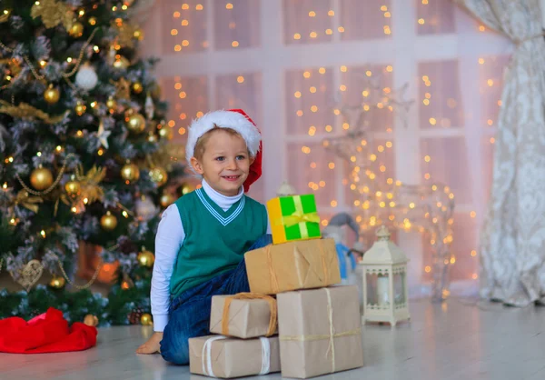 Μικρό αγόρι με τα Χριστούγεννα παρουσιάζει σε διακοσμημένο σαλόνι — Φωτογραφία Αρχείου