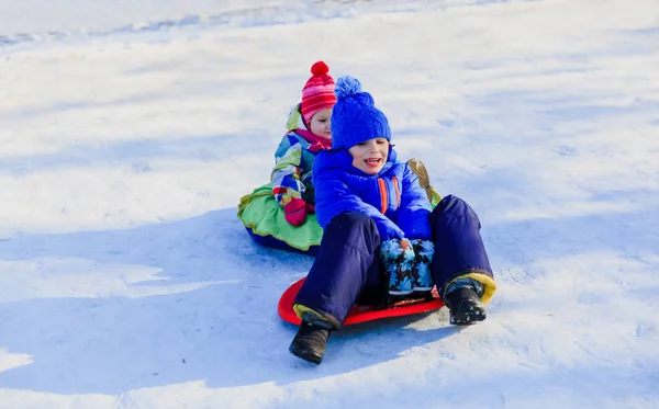 Mały chłopiec i dziewczynka przesuwne w snow zima — Zdjęcie stockowe