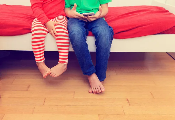 Bruder und Schwester schauen aufs Handy, konzentrieren sich auf die Füße — Stockfoto