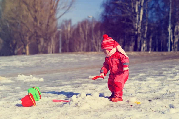 Little girl digging snow in winter, kids activities — Stock Photo, Image