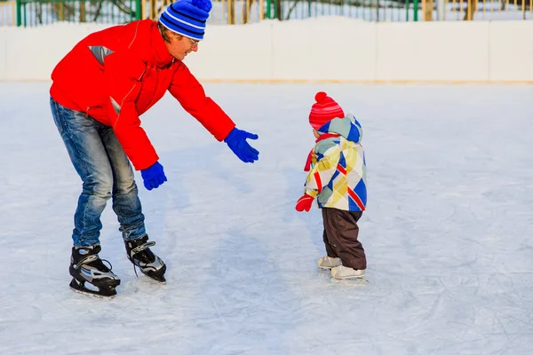 Отец учит маленькую дочь кататься на коньках зимой — стоковое фото