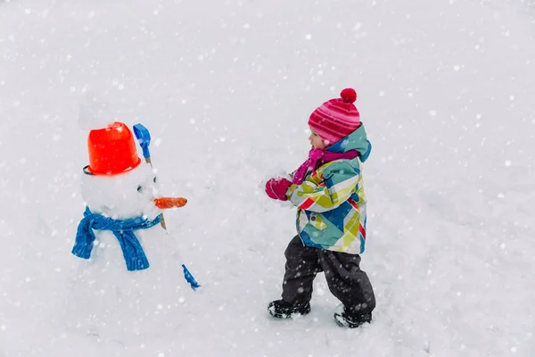 Little girl building snowman in winter nature — Stock Photo, Image