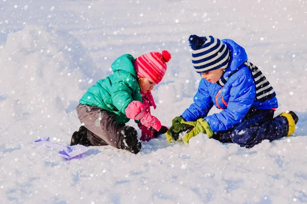 Little boy and girl digging snow in winter — Stock Photo, Image