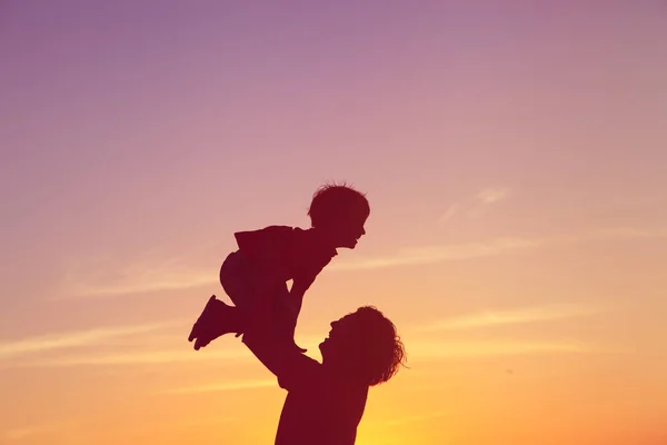 Father and little son silhouettes play at sunset sky — Stock Photo, Image