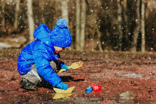 Anak kecil bermain dengan perahu kertas di musim dingin — Stok Foto