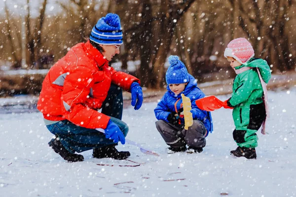 Father and kids digging snow in winter nature — Stock Photo, Image