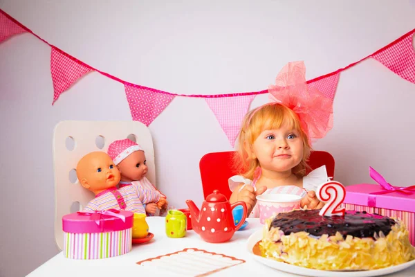 Menina bonito com doces e bonecas na festa de aniversário — Fotografia de Stock