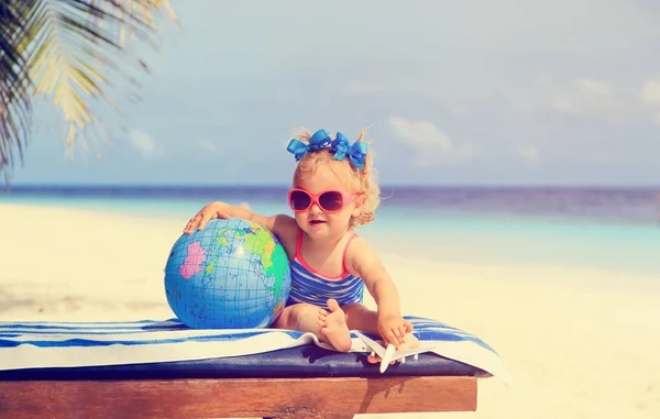 Familie reizen - meisje met globe en speelgoed vliegtuig op strand — Stockfoto