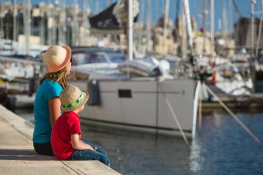 family travel - mother and son looking at boats in port clipart