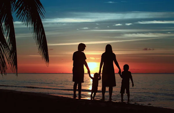 Família feliz com duas crianças na praia do por do sol — Fotografia de Stock