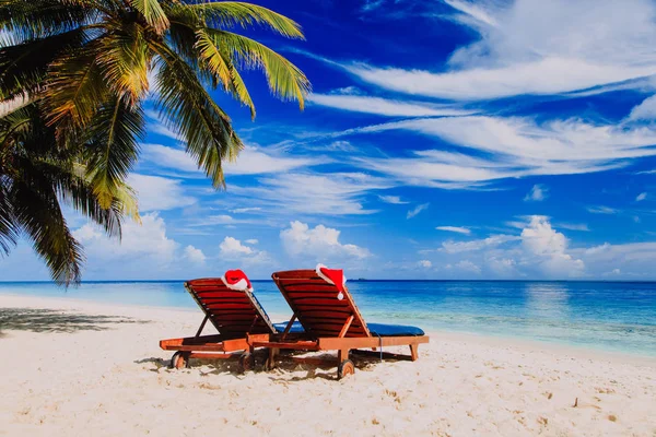 Christmas on beach -chair lounges with Santa hats at sea