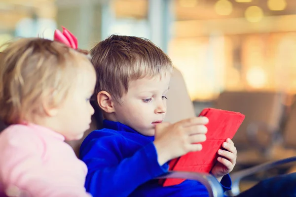 Junge und Mädchen schauen auf Touchpad auf Reisen im Flughafen — Stockfoto