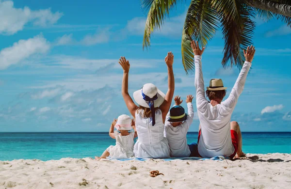 Gelukkige familie met twee kinderen handen omhoog op het strand — Stockfoto