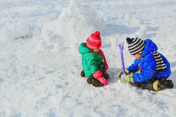 Little boy and girl digging snow in winter — Stock Photo, Image