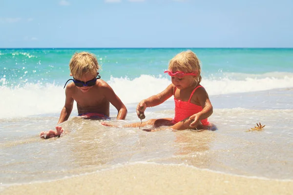小さな男の子と女の子が砂浜で遊んでいます — ストック写真