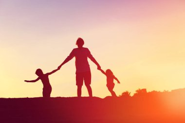 Baba ile oğlu ve kızı siluetleri oyun gün batımında