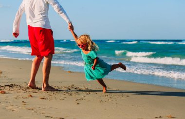 Baba ve küçük kız sahilde oynuyorlar.