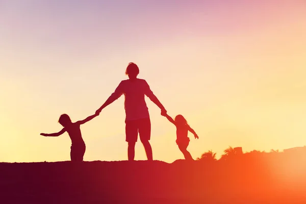 Padre con figlio e figlia silhouette giocare al tramonto — Foto Stock