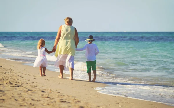 Šťastná babička s dětmi - malý chlapec a dívka-na pláži — Stock fotografie